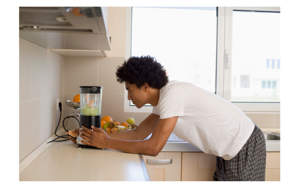 A man using a blender in a kitchen to prepare a smoothie, - looking closely at the blender as if trying to understand how it works. Emphasizes the need for ease of use